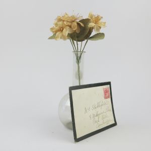 Flask of silk flowers & mourning envelope